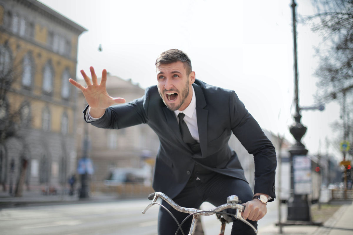 Man wearing a suit and riding a bike, late and desperate